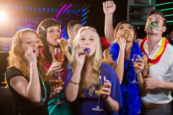 Grupo de amigos soplando cuerno de fiesta en el bar —  Fotos de Stock