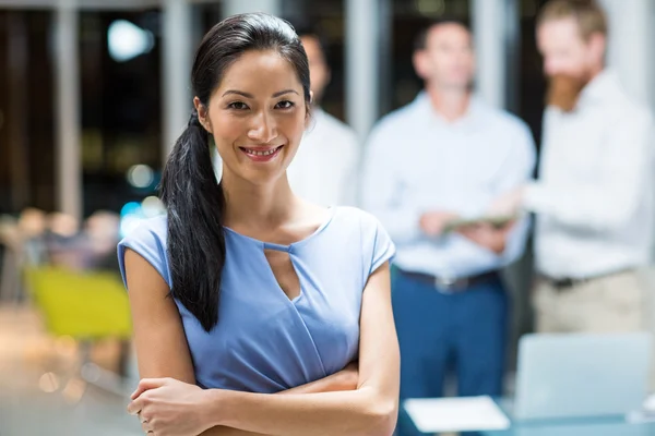 Affärskvinna står med armarna korsade i office — Stockfoto