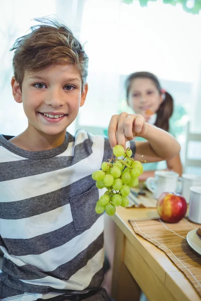 Lachende jongen houdt een tros druiven — Stockfoto