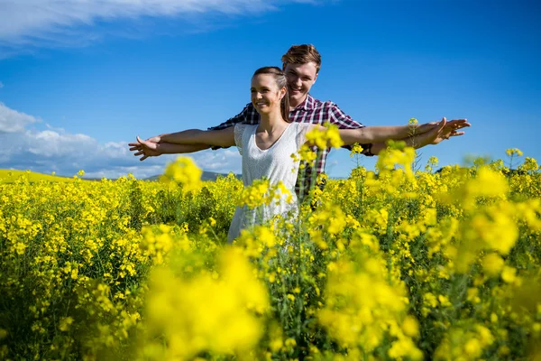 Pareja con los brazos extendidos en el campo de mostaza —  Fotos de Stock