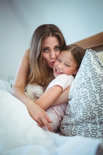 Mãe beijando filha na cama — Fotografia de Stock