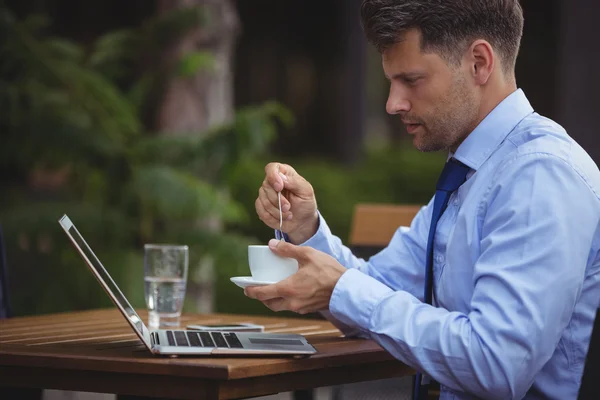 Homem de negócios tendo chá ao usar laptop — Fotografia de Stock