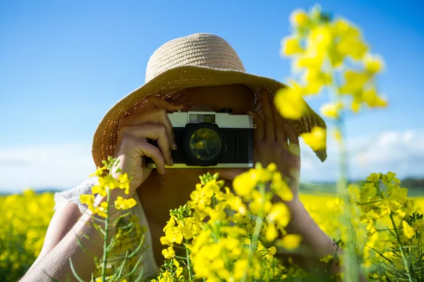 Mujer tomando fotos de la cámara en el campo de mostaza —  Fotos de Stock