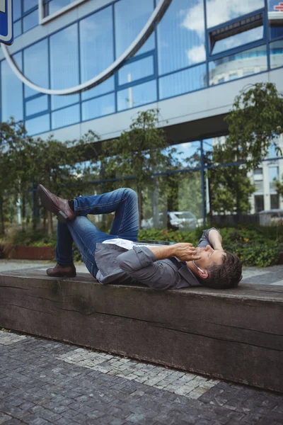 Бизнес-менеджер лежит на дереве и слушает музыку — стоковое фото