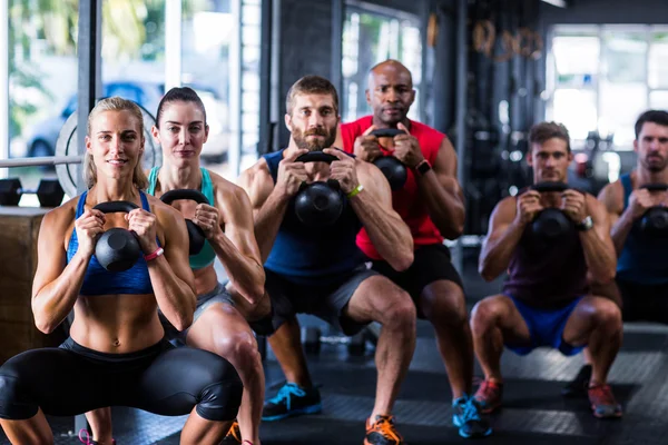 Lidé hospodářství kettlebells v tělocvičně — Stock fotografie