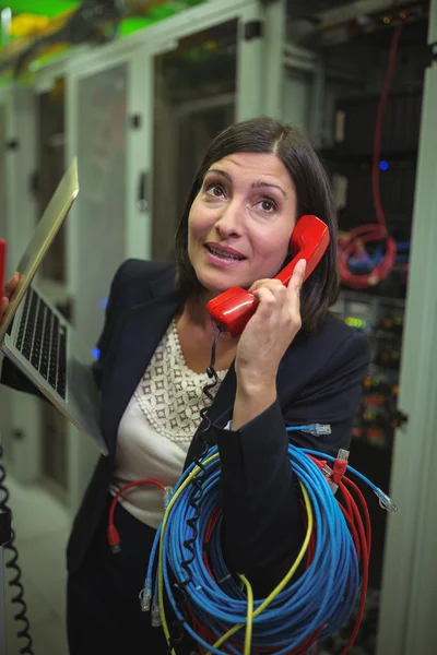 Technician talking on phone while analyzing server — ストック写真