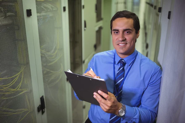 Technician maintaining record of rack mounted server — Stockfoto