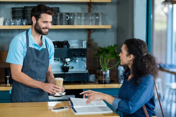 Ober serveren van koffie aan klant aan tafel — Stockfoto