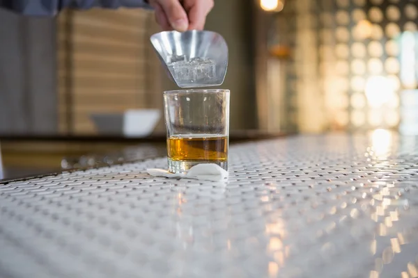 Servitören lägger isbitar i en whisky-glas med en skopa — Stockfoto