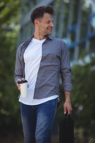 Business executive holding disposable cup and bag — Stock Photo, Image