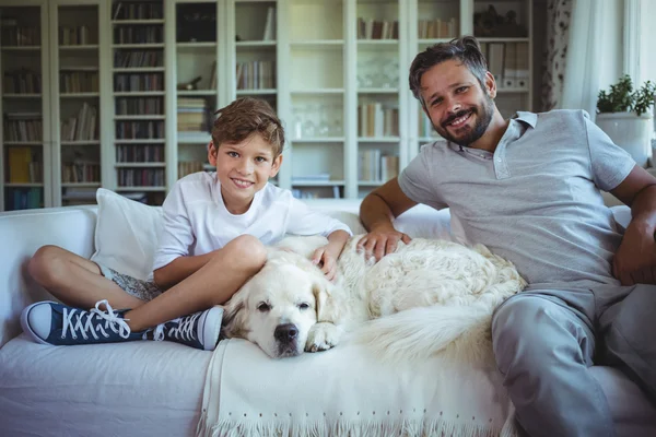 Father and son on sofa with pet dog — Stockfoto