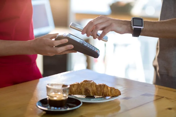Человек оплачивает счета через смартфон с использованием технологии NFC — стоковое фото