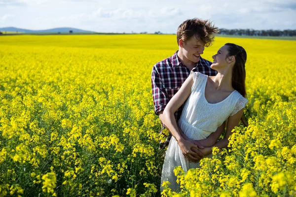 Couple standing in mustard field — Stock Photo, Image