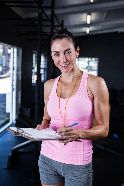 Fitness instructor holding clipboard in gym — Stock Photo, Image