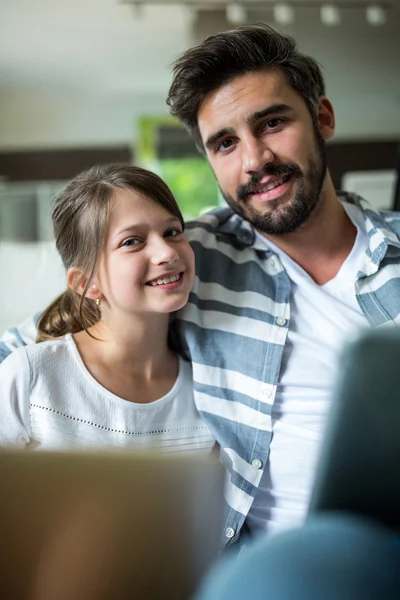 Portret van vader en dochter met laptop en digitale tablet in de woonkamer — Stockfoto