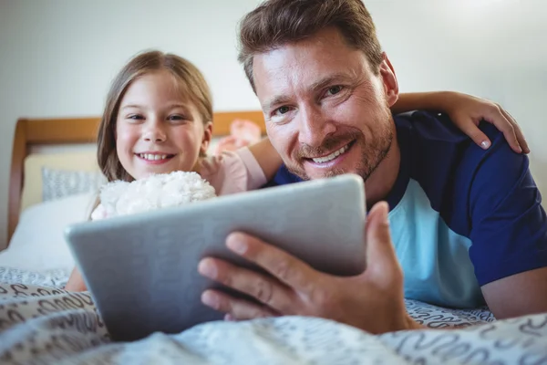 Père couché avec sa fille utilisant une tablette — Photo