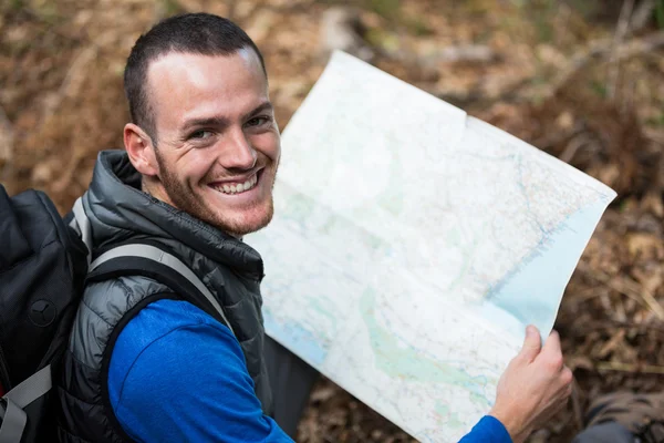 Male hiker holding a map in forest — Stock Photo, Image