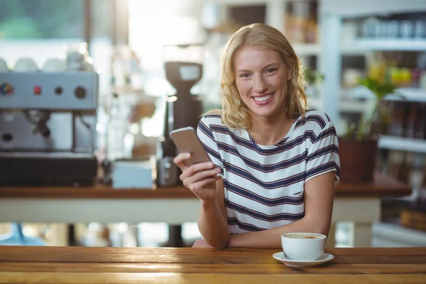 Mulher usando telefone enquanto toma café — Fotografia de Stock