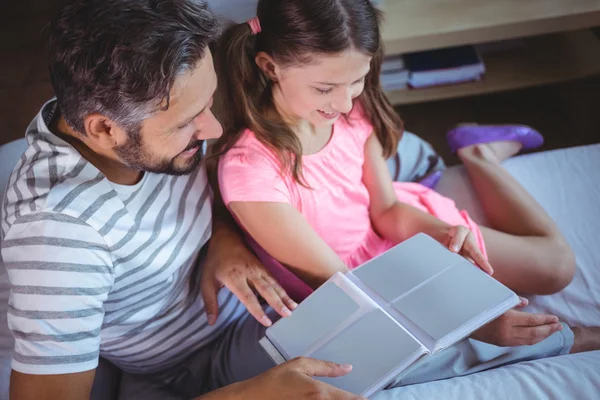 Father and daughter looking photo album on bed — Stockfoto