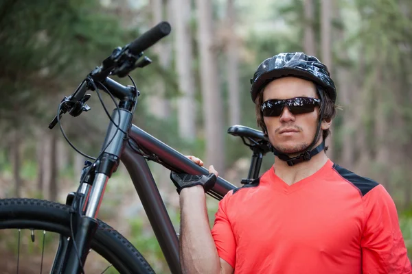 Retrato de ciclista de montanha masculino transportando bicicleta na floresta — Fotografia de Stock