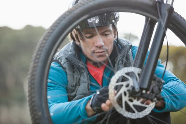 Mountain biker examining front wheel — Stock Photo, Image