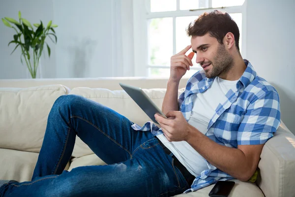 Mann benutzt Tablet beim Entspannen auf Sofa — Stockfoto