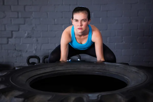 Athlète féminine sérieuse ramassant pneu — Photo