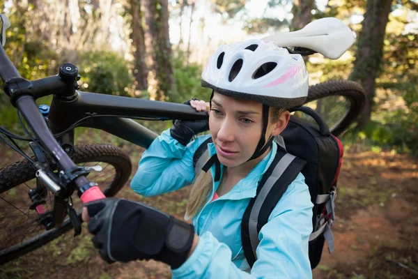Feminino mountain biker carregando sua bicicleta — Fotografia de Stock