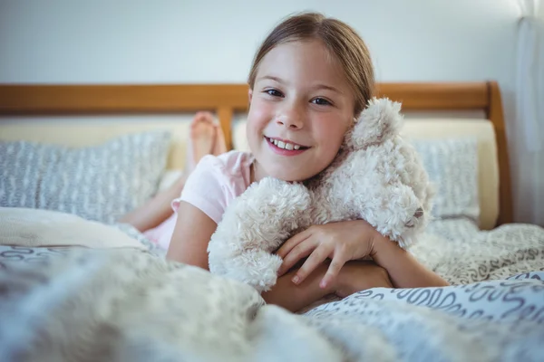 Menina feliz deitado com um ursinho de pelúcia — Fotografia de Stock