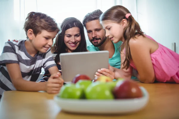 Семья с помощью цифрового планшета во время сидения за столом — стоковое фото