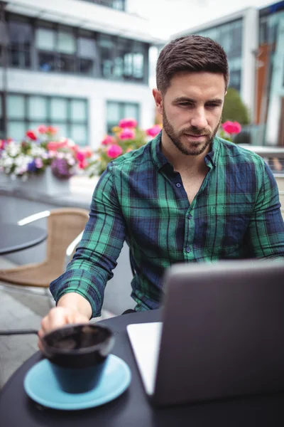 Businessman using laptop while having coffee — Stock Photo, Image