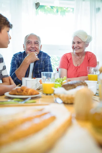 Junge und Großeltern sitzen am Frühstückstisch — Stockfoto