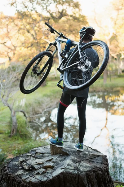 Motociclista de montanha masculino transportando bicicleta — Fotografia de Stock