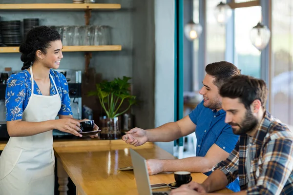 Serveerster serveren een kopje koffie aan klant — Stockfoto