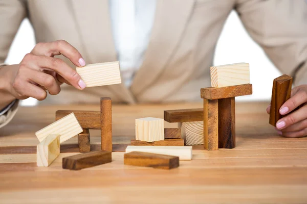 Businesswoman placing wooden block on tower — Stock Photo, Image