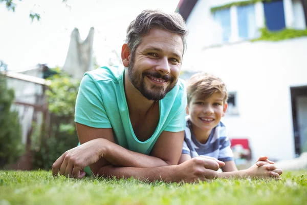 Pai e filho deitados na grama — Fotografia de Stock