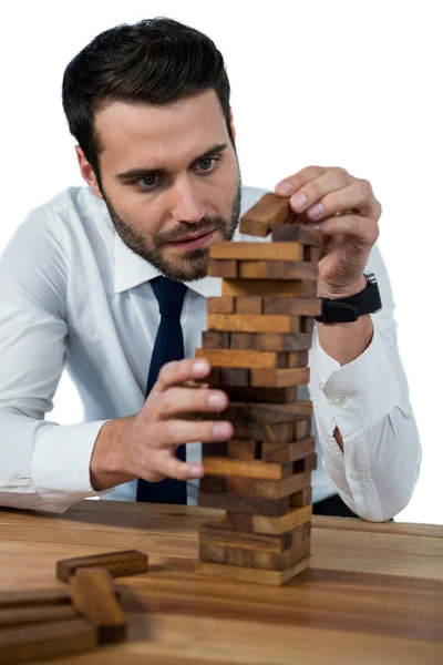 Businessman placing wooden block on tower — Stock Photo, Image