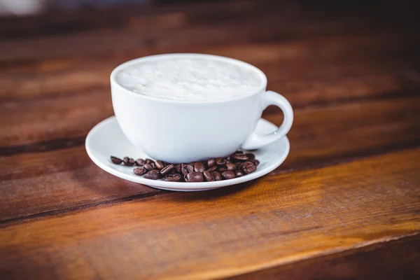 Coffee cup and beans on a table — Stock Photo, Image