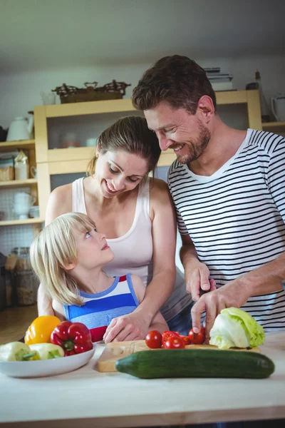 Family looking at each other while preparing salad in the kitchen — ストック写真