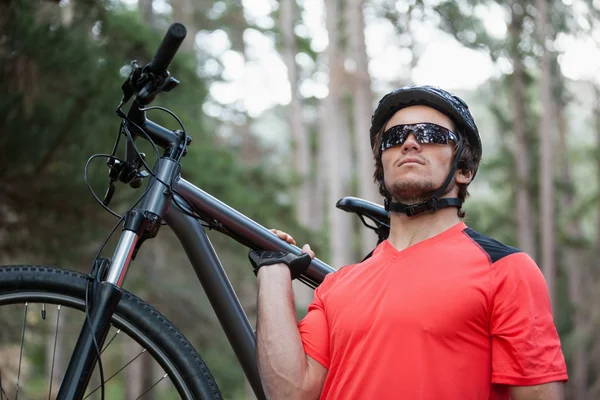 Male mountain biker carrying bicycle in the forest — Stock Photo, Image