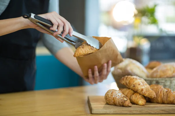 Serveerster croissants verpakking in papieren zak in café — Stockfoto
