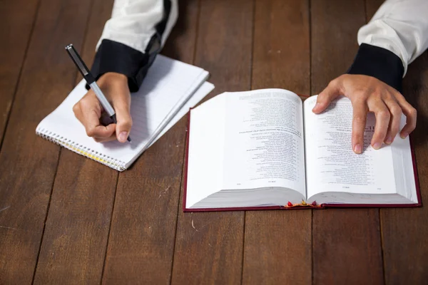 Vrouw met een Bijbel schrijven op Kladblok — Stockfoto