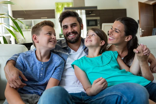 Family sitting with arm around on sofa — ストック写真