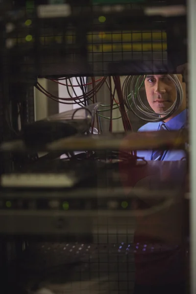 Technician checking cables in rack mounted server — ストック写真