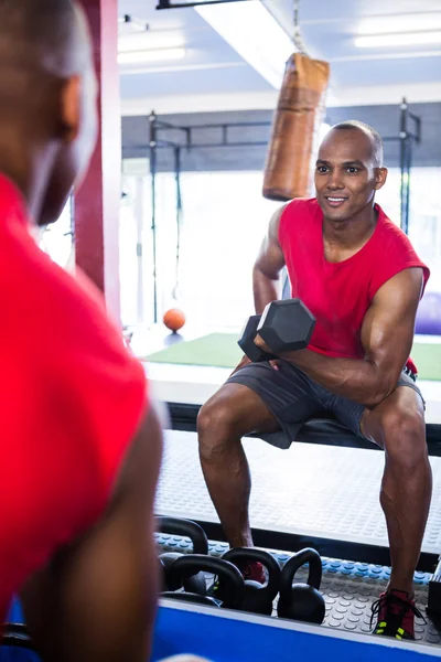 Hombre sonriendo mientras hace ejercicio con pesas — Foto de Stock