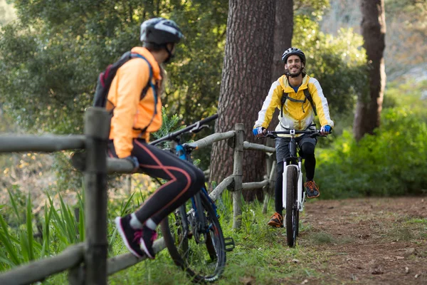 Motociclista maschio in bicicletta mentre motociclista femmina sulla recinzione — Foto Stock