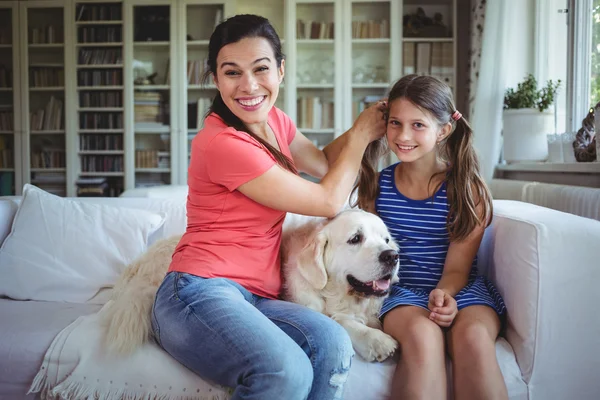 Mother sitting on sofa and tying daughters hair — ストック写真