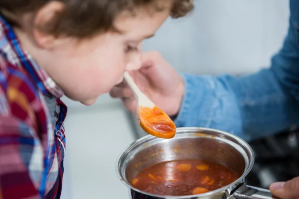 Zoon proeven van voedsel in de keuken — Stockfoto