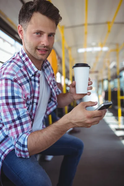 Handsome man using phone while having coffee — Stock fotografie