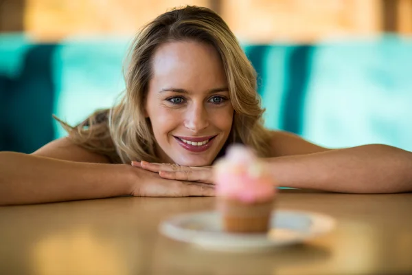 Mujer mirando cupcake en plato —  Fotos de Stock